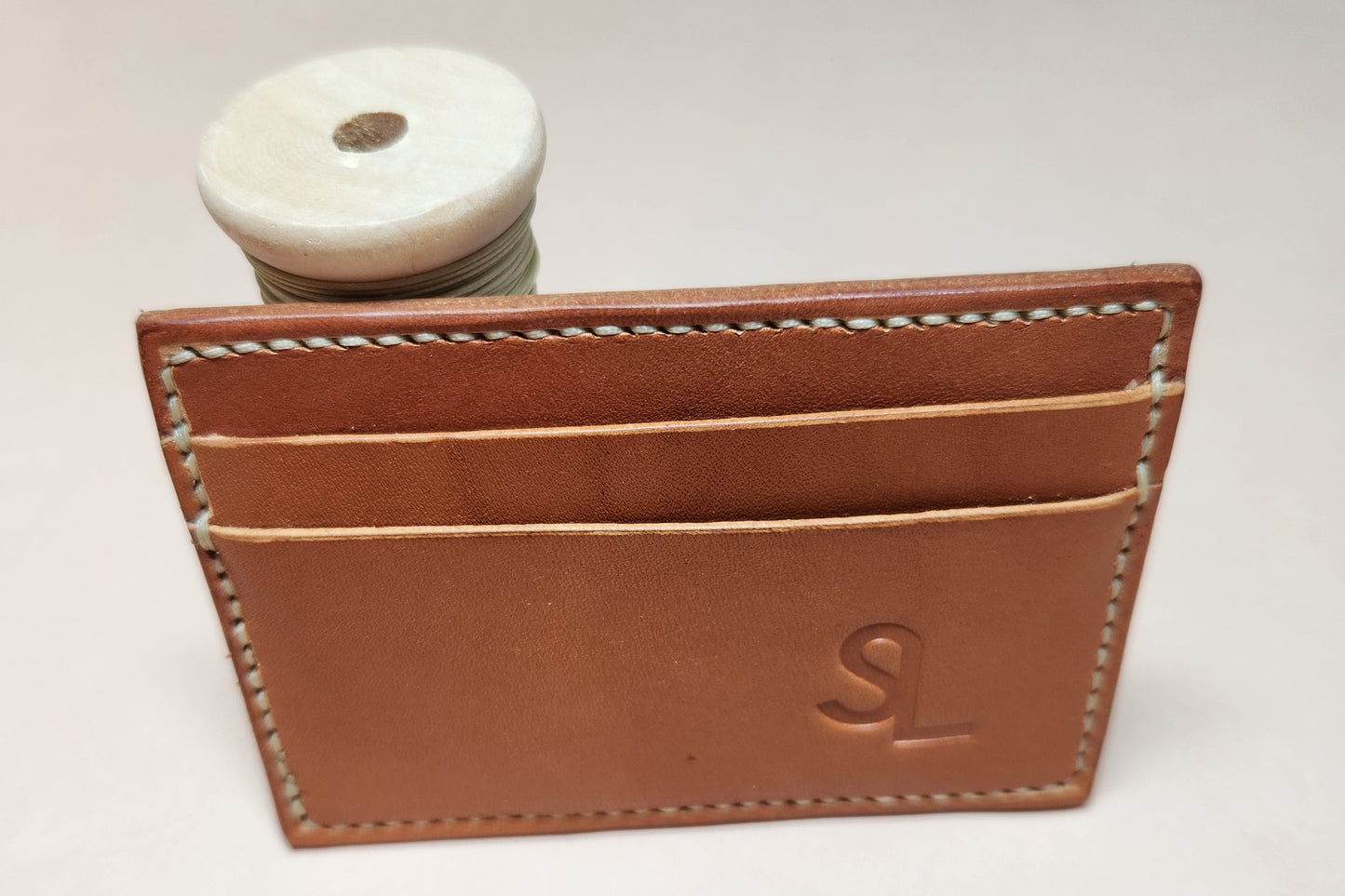 Brown leather cardholder with stitching detail on a light gray background