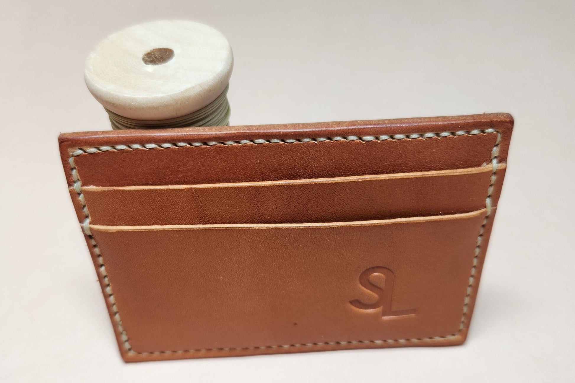 Brown leather cardholder with stitching detail on a light gray background