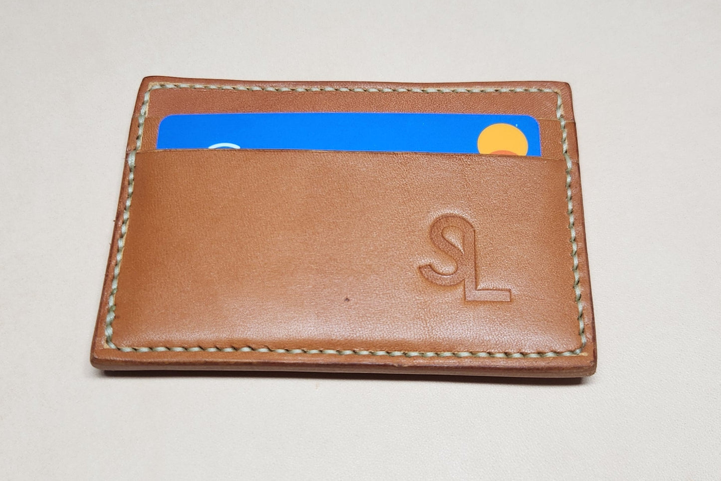 Brown leather cardholder with blue accent on a light gray background